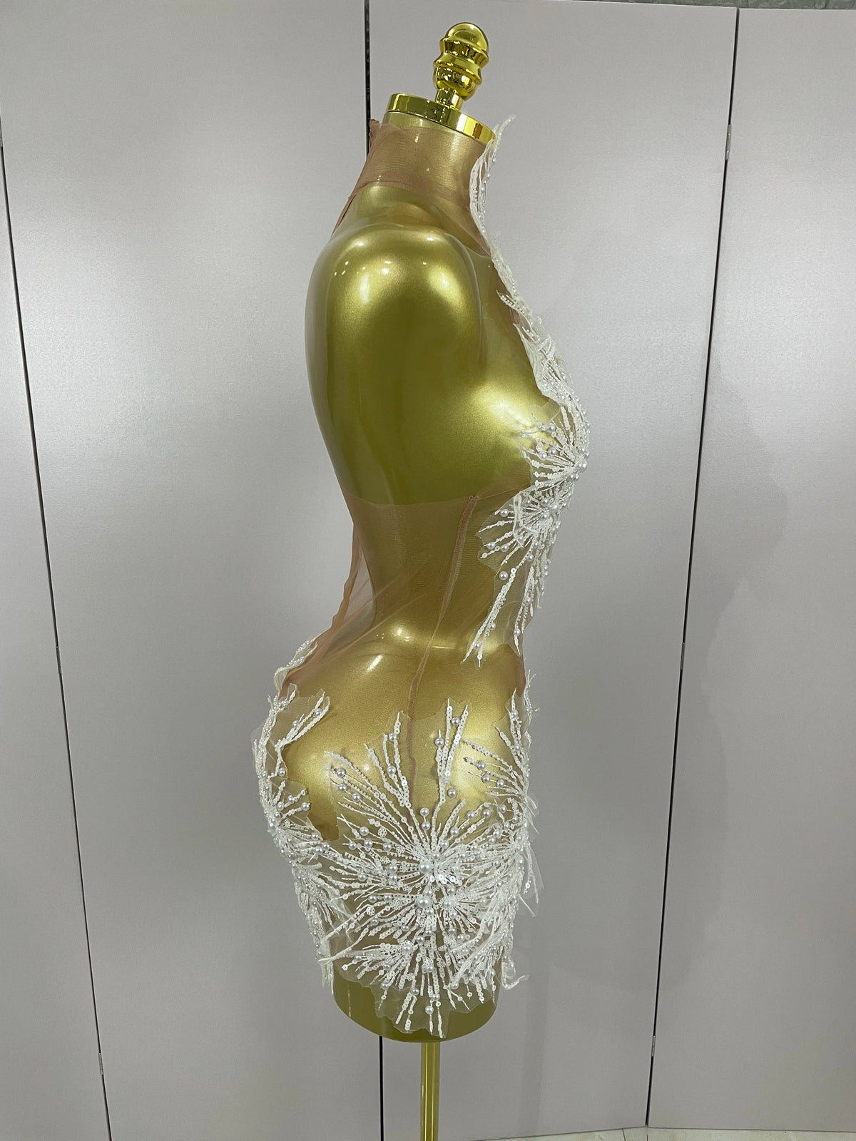Gold mannequin torso with decorative elements on a plain background